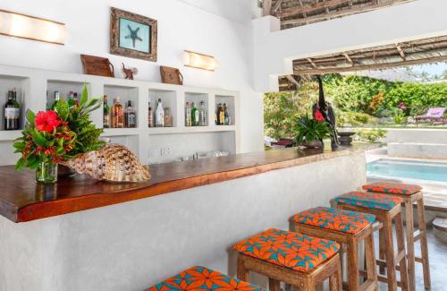 a bar with stools and a counter with wine bottles at Hekaya Zanzibar in Pingwe
