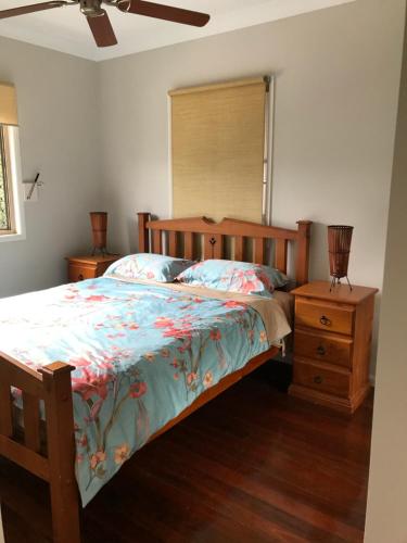 a bedroom with a wooden bed and a night stand at Tamborine Mountain Accommodation in Mount Tamborine