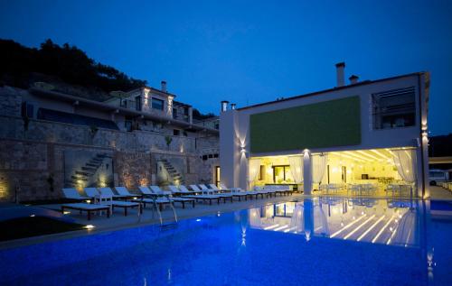 a swimming pool with chairs and a large screen at Salvator Villas & Spa Hotel in Parga