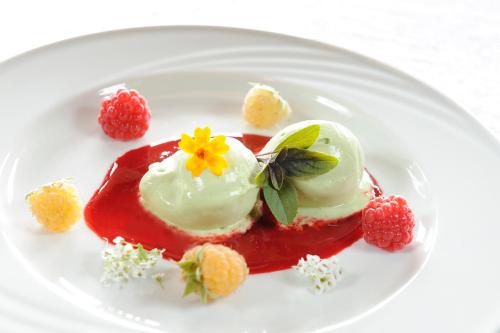 a white plate with a dessert with red sauce and berries at Naturhotel Alpenrose in Millstatt