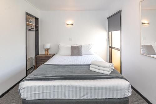 a bedroom with a large bed with towels on it at Burwood Motel in Whanganui
