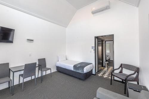 a room with a bed and some chairs and a table at Burwood Motel in Whanganui