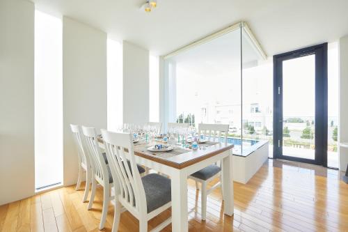 a white dining room with a table and chairs at RIZOZAIZEN MOTOBU B in Motobu