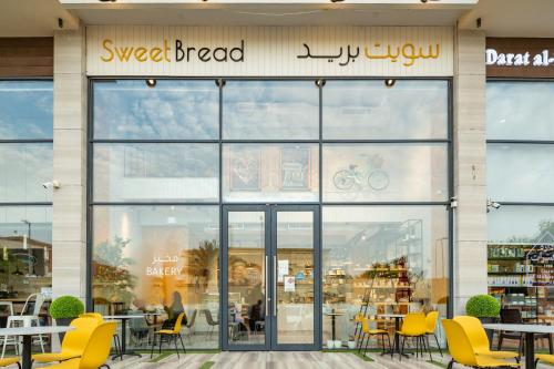 a store front with yellow chairs and tables at Eden Residence in Jeddah