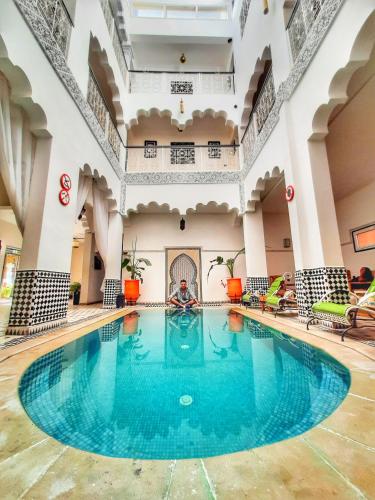 ein Pool in der Mitte eines Gebäudes mit Menschen im Wasser in der Unterkunft Hotel Riad Amlal in Ouarzazate