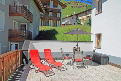 a patio with a table and chairs and an umbrella at Chasa Arlu in Samnaun