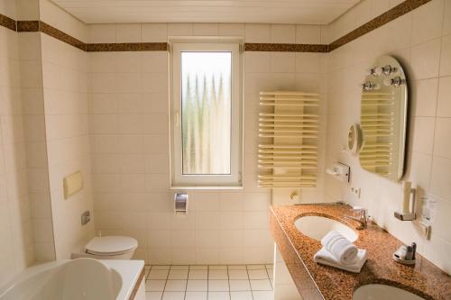 a bathroom with two sinks and a tub and a toilet at Hotel-Restaurant Zur Krone in Löhnberg