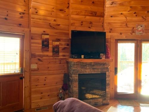 a living room with a fireplace and a flat screen tv at Heavenly View Cabin in McCookville