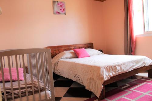 a bedroom with a crib and a bed with pink pillows at CASAMELIAS "casappart 2" in Cilaos