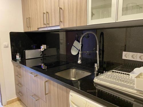 cocina con fregadero y encimera negra en Apartamento Luxury & Top sea view, en Alicante