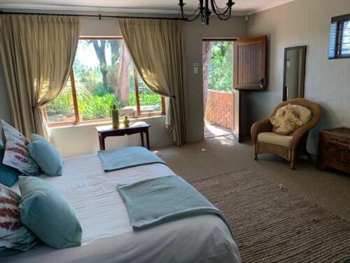 a bedroom with a bed and a chair and windows at Gerald's Gift Guest House in Addo