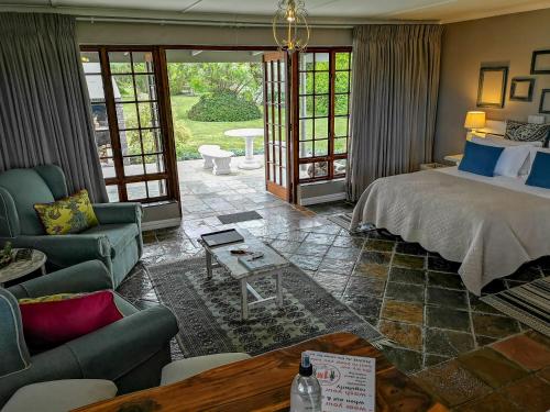 a bedroom with a bed and a couch and a table at Tsitsikamma Gardens Cottages Self-catering Cottages in Sanddrif