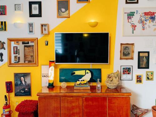 ein Wohnzimmer mit einem TV an einer gelben Wand in der Unterkunft Zili Pernambuco - Hostel Pousada in Recife