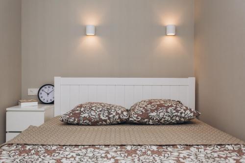 two pillows sitting on top of a bed with a clock at Apart-hotel I. Sirko New Building 3 floor in Sumy