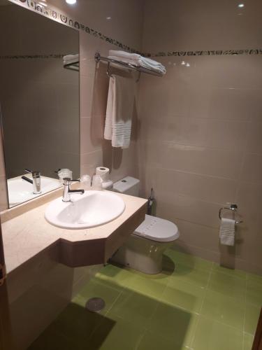 a bathroom with a sink and a toilet and a mirror at Motel Acropolis in Camponaraya