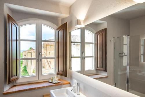 un bagno con due finestre, lavandino e doccia di Relais Le Macine Di Stigliano a Sovicille