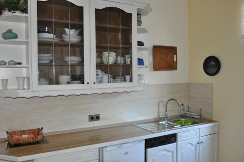 uma cozinha com armários brancos e um lavatório em Feriendomizil Auszeit em Wernigerode