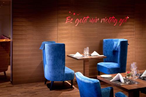 a restaurant with blue chairs and tables and a sign that reads be seated with nothing at Ayurveda Resort MANDIRA in Bad Waltersdorf
