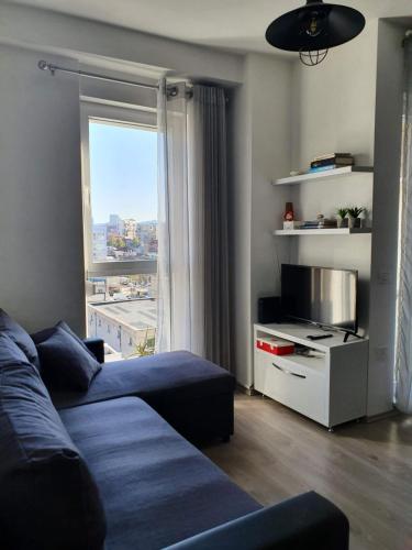 a living room with a couch and a large window at Rovena's Apartment - free parking in Tirana