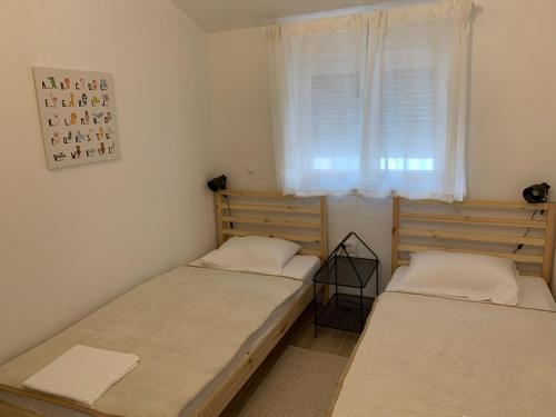 2 camas en una habitación pequeña con ventana en Apartman Filipi, en Sveti Filip i Jakov