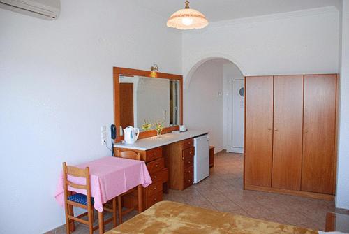 een keuken met een tafel, een wastafel en een spiegel bij Aloha Hotel in Agios Gordios