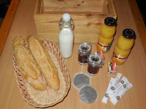 un tavolo con un cesto di pane e una bottiglia di latte di Le chalet bois de Célio a Coux