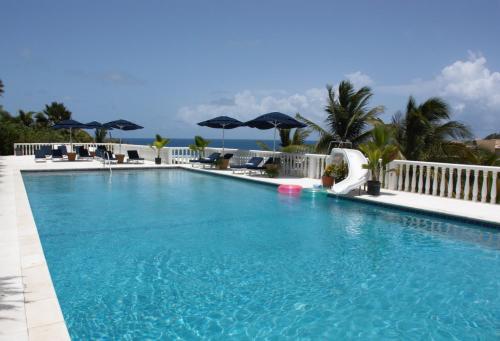 a large swimming pool with chairs and umbrellas at Princess Heights Luxury Condo Hotel in Dawn Beach