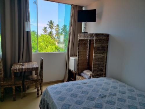 1 dormitorio con cama y ventana con vistas en Pousada Costa Tropical, en Tamandaré