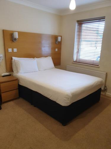 a bedroom with a large bed with white sheets and a window at Reading Budget Apartments in Reading