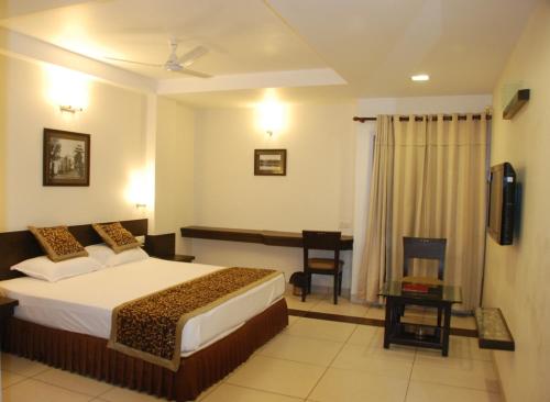 Cette chambre comprend un lit et un bureau. dans l'établissement Grand Ashirwad Beacon, à Bhopal