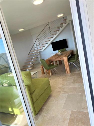 a living room with a green couch and a desk and stairs at Villa M - Your business & holiday apartment in Sibenik in Šibenik