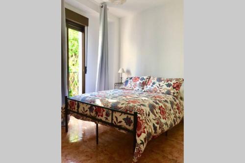 a bedroom with a bed with a floral bedspread and a window at Apartamento Toril-Casco Histórico in Córdoba