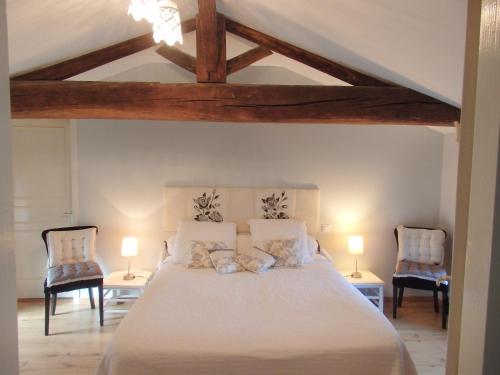 una camera da letto con un grande letto con due sedie di Chambres d'Hôtes Le Tilleul a Saint-Hilaire-des-Loges