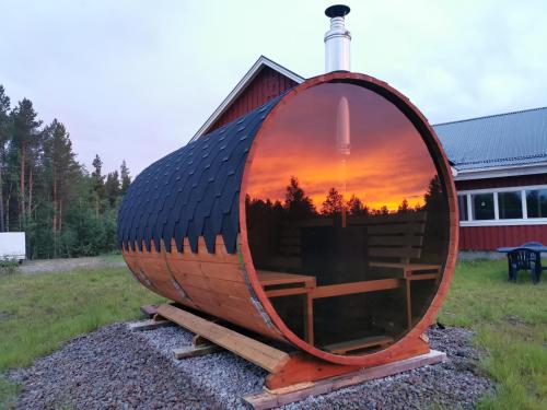 a barrel with a sunset in it in front of a house at Villa Björklund - Lakeview Apartment in Arjeplog