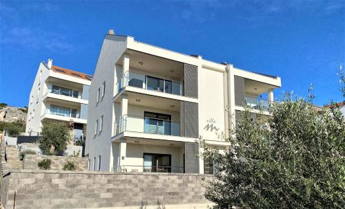 a white apartment building on top of a stone wall at Villa M - Your business & holiday apartment in Sibenik in Šibenik