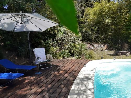 a deck with two chairs and an umbrella next to a swimming pool at Los Mochos Portezuelo in Punta del Este