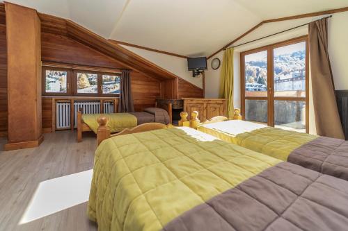 a bedroom with two beds and a large window at Hotel Stella Alpina in Sauze dʼOulx