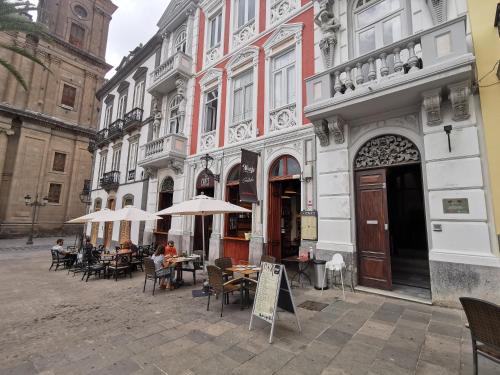 Santa Ana Suite & Rooms في لاس بالماس دي غران كاناريا: مجموعة من الطاولات والكراسي أمام المبنى