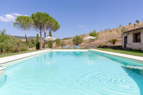 a large swimming pool with blue water in a yard at Villa Il Turchetto in Saturnia