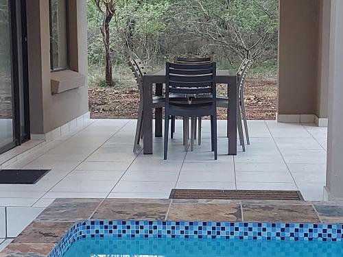a table and chairs on a patio with a pool at 3714 @Ribbok in Marloth Park