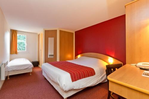 een hotelkamer met een bed met een rode muur bij Prest'Hôtel Epinal 88150 CHAVELOT in Épinal
