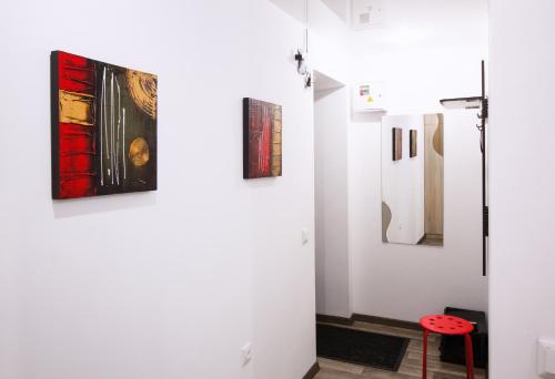 a room with white walls with paintings and a red stool at Apartment on Soborniy 85 in Oleksandriya
