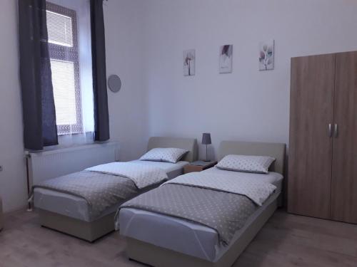 two beds in a room with two windows at Studio apartman Ela in Travnik