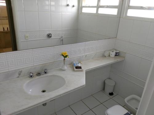 a white bathroom with a sink and a toilet at A2 suites - Hotel e Motel in Brasilia