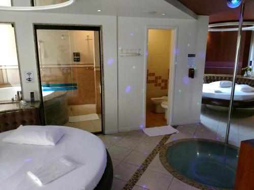 a bathroom with a tub and a shower and a bed at A2 suites - Hotel e Motel in Brasilia