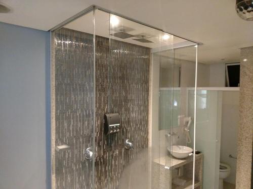 a bathroom with a glass shower with a sink at A2 suites - Hotel e Motel in Brasilia
