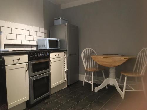 a kitchen with a stove and a table with chairs at Blue Sky Cottage in Matlock