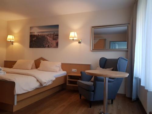 Habitación de hotel con cama, mesa y sillas en Hotel Penterknapp en Bramsche