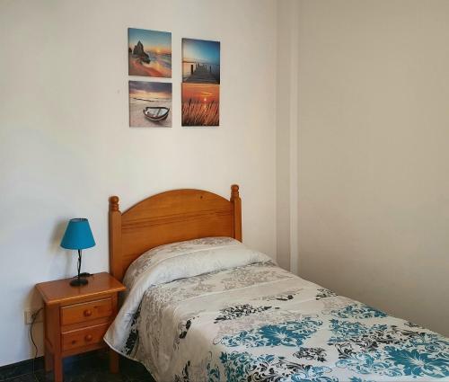 アリナガにあるVivienda FRALEMAR Arinaga.のベッドルーム1室(ベッド1台付)が備わります。壁に2枚の写真が飾られています。