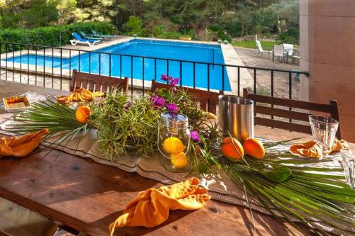 a wooden table with oranges and flowers on it with a pool at Finca Es Collet in Felanitx